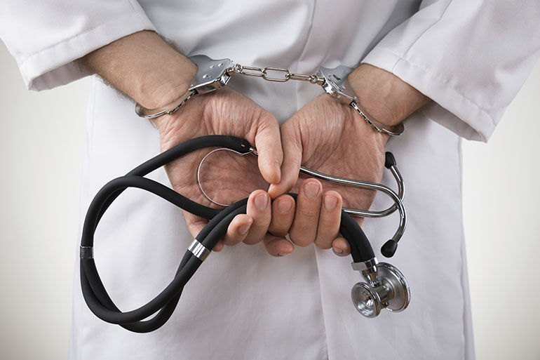 Close-up Of Doctor Hands With Stethoscope In Handcuffs