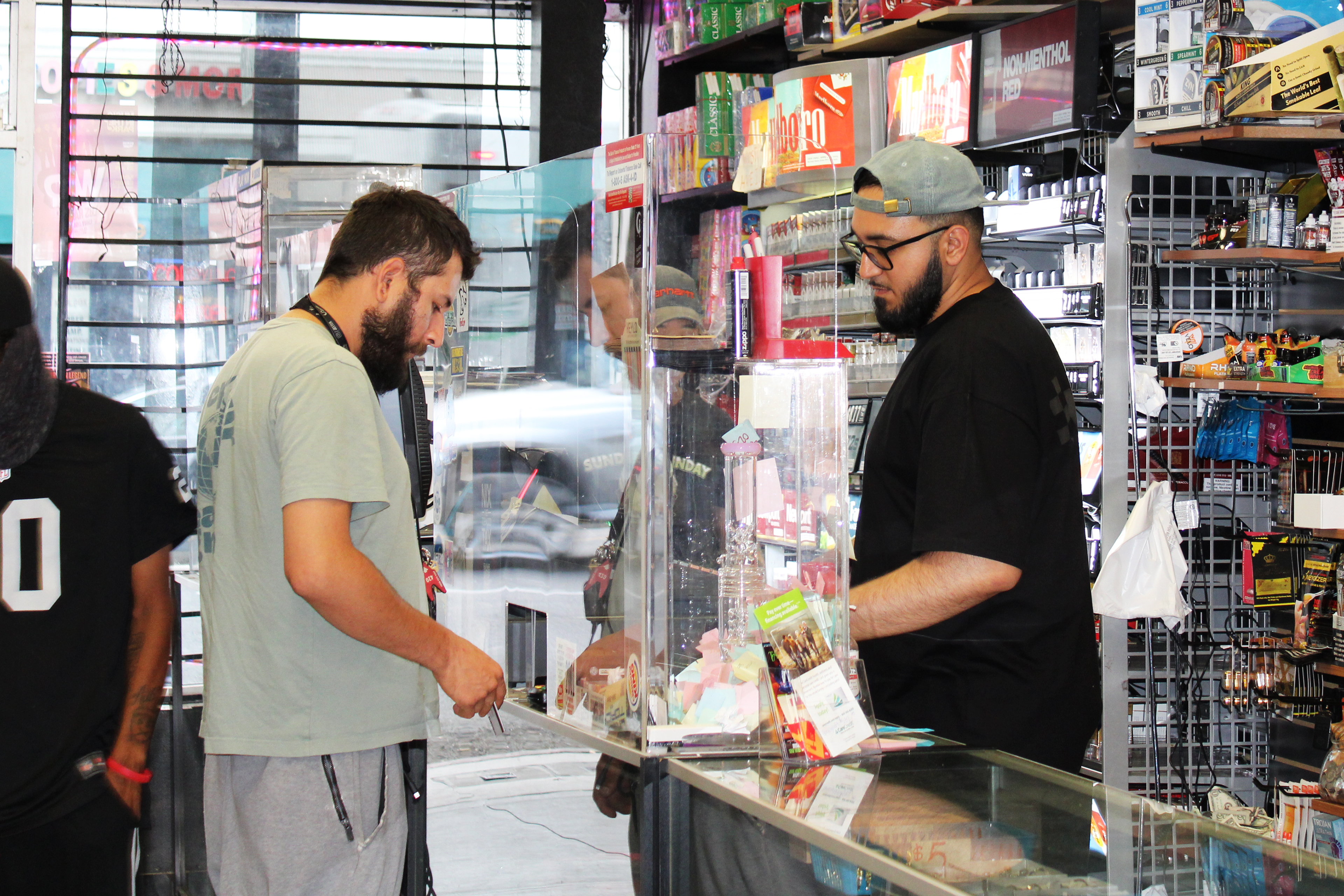 A photo shows John Tokhi with a customer inside of a smoke shop.