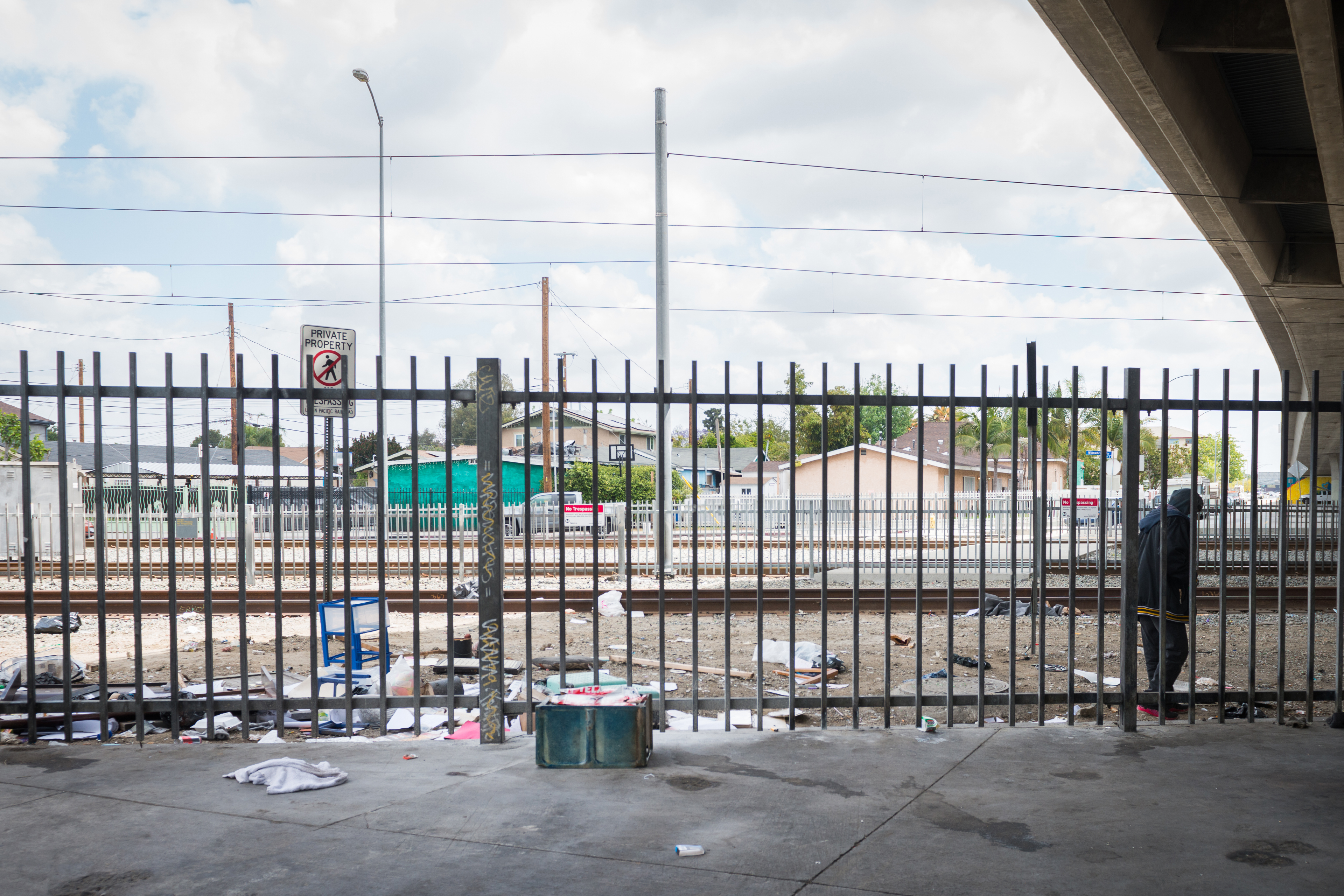 A photo shows a sidewalk littered with trash. Behind a gate is a sign that reads, "Private property, no trespassing."