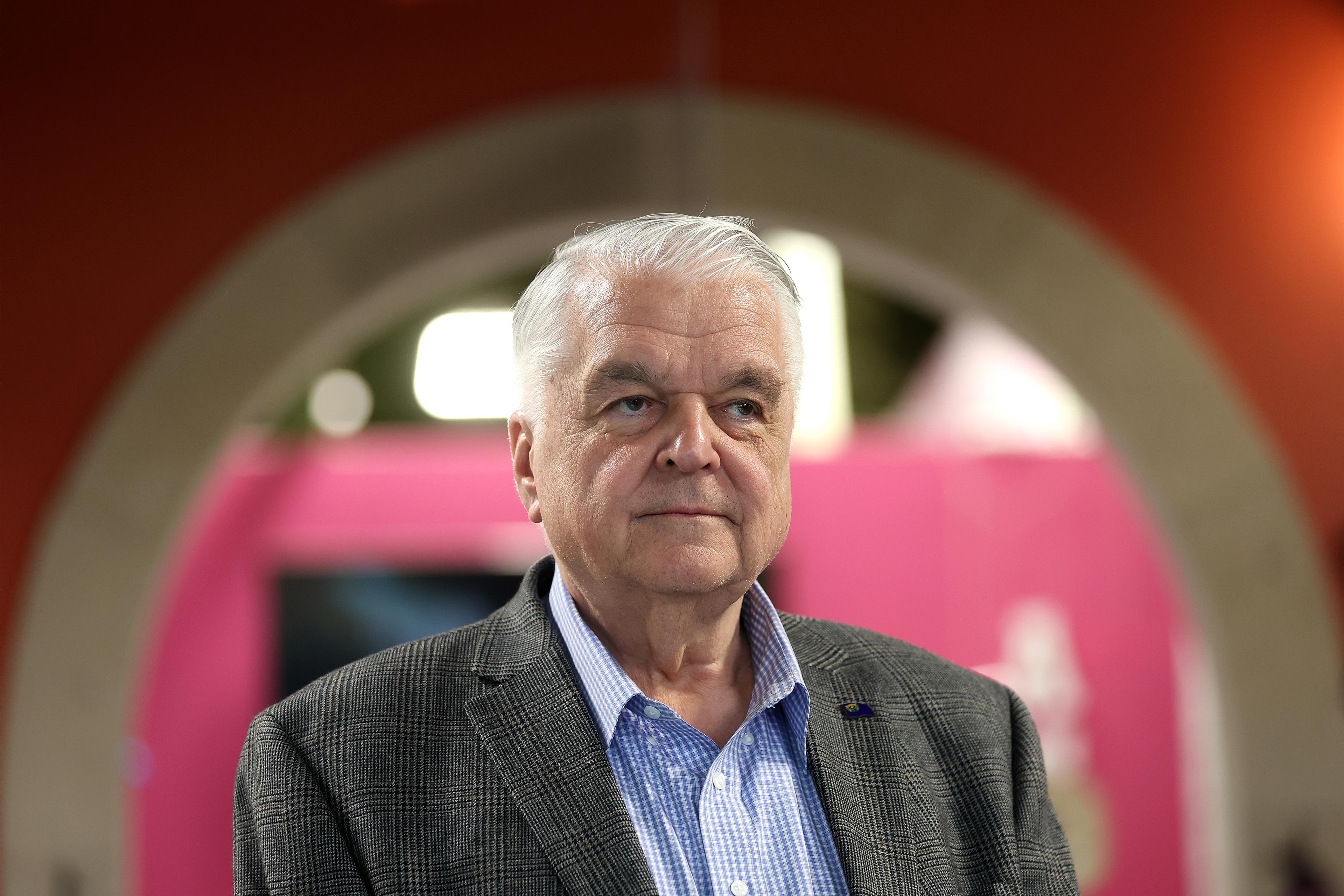 A photo shows Gov. Steve Sisolak standing indoors.