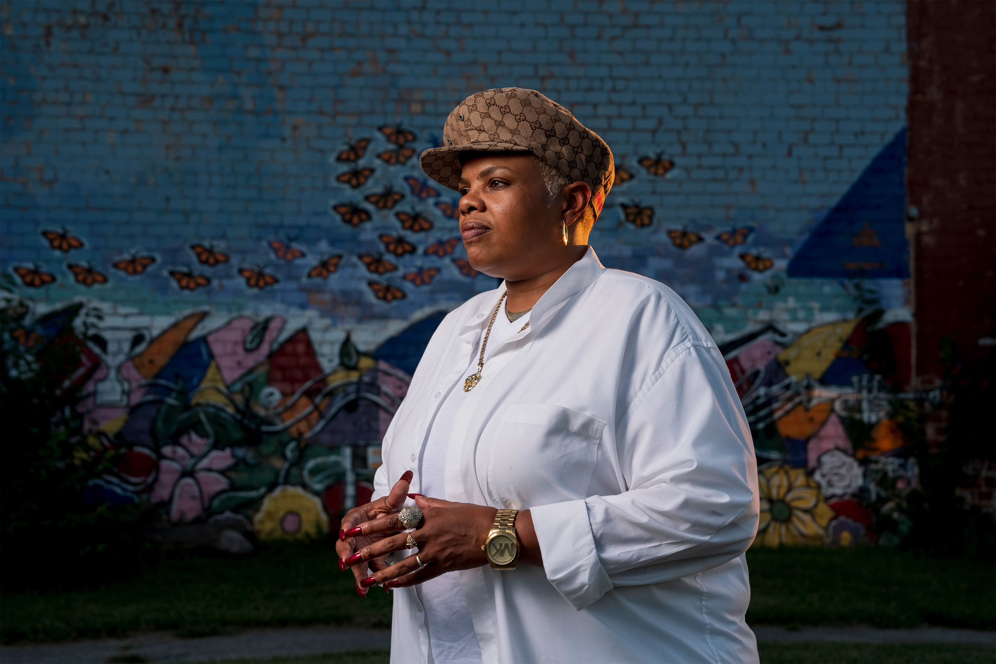 A photo shows Terra Jenkins posing for a photograph. She stands in front of a mural of butterflies painted on a brick wall.