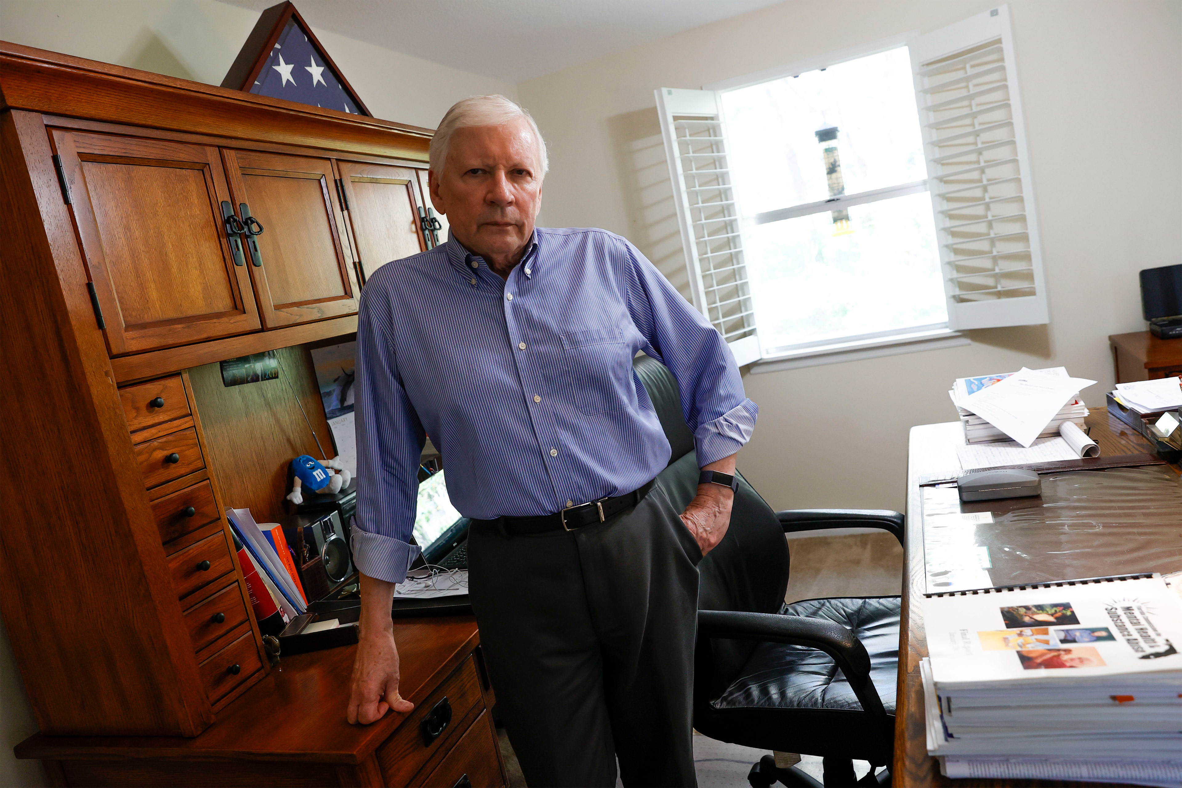 A photo of a man posing for a portrait in his office.