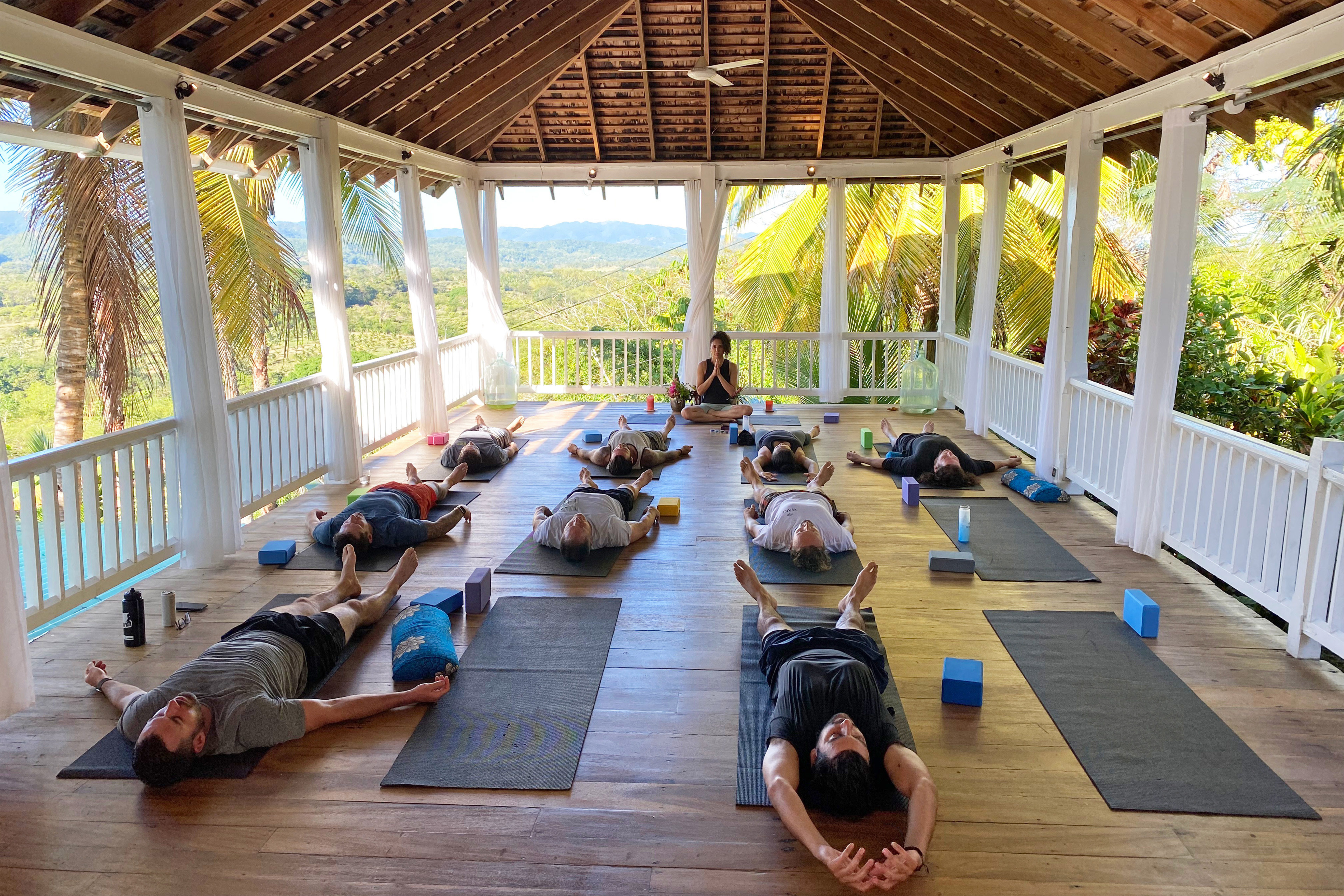 A photo of people practicing yoga on mats inside of a gazebo.