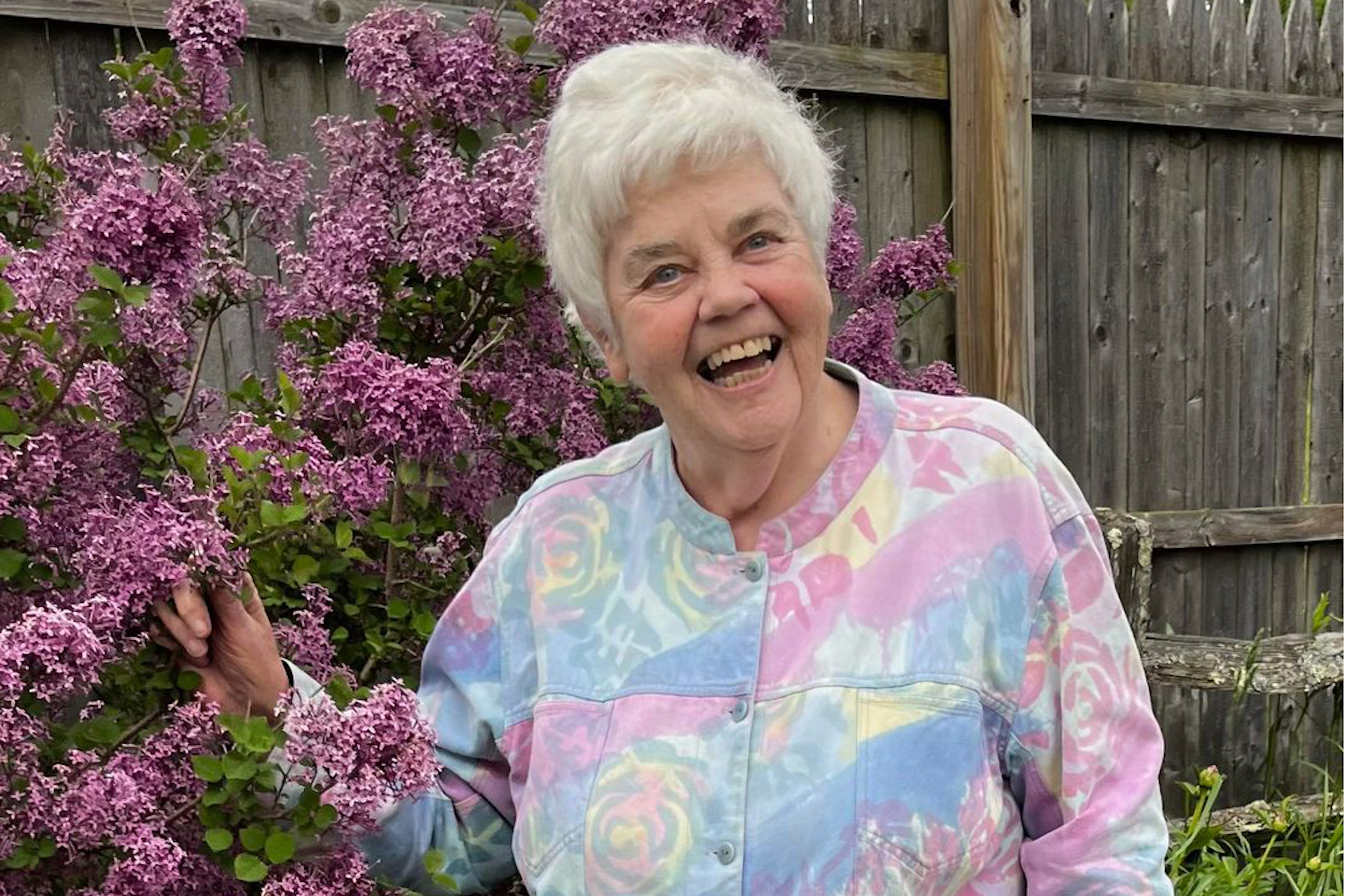 A photo of an older woman smiling outside.
