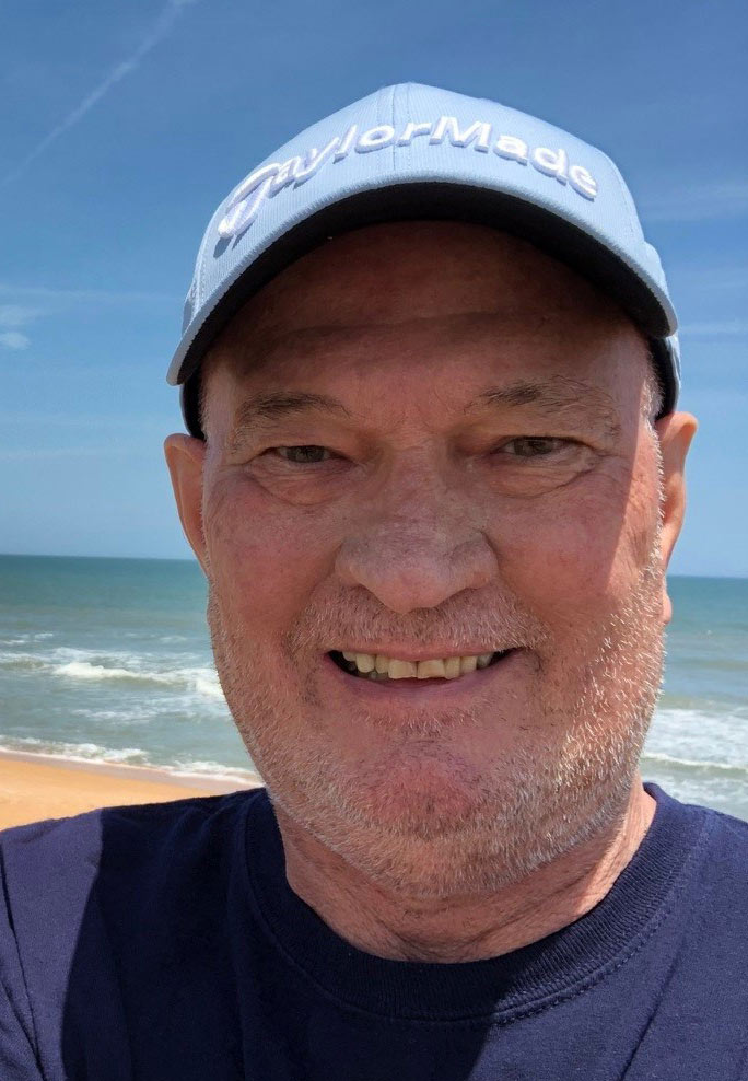 A photo of a man standing outside by the beach.
