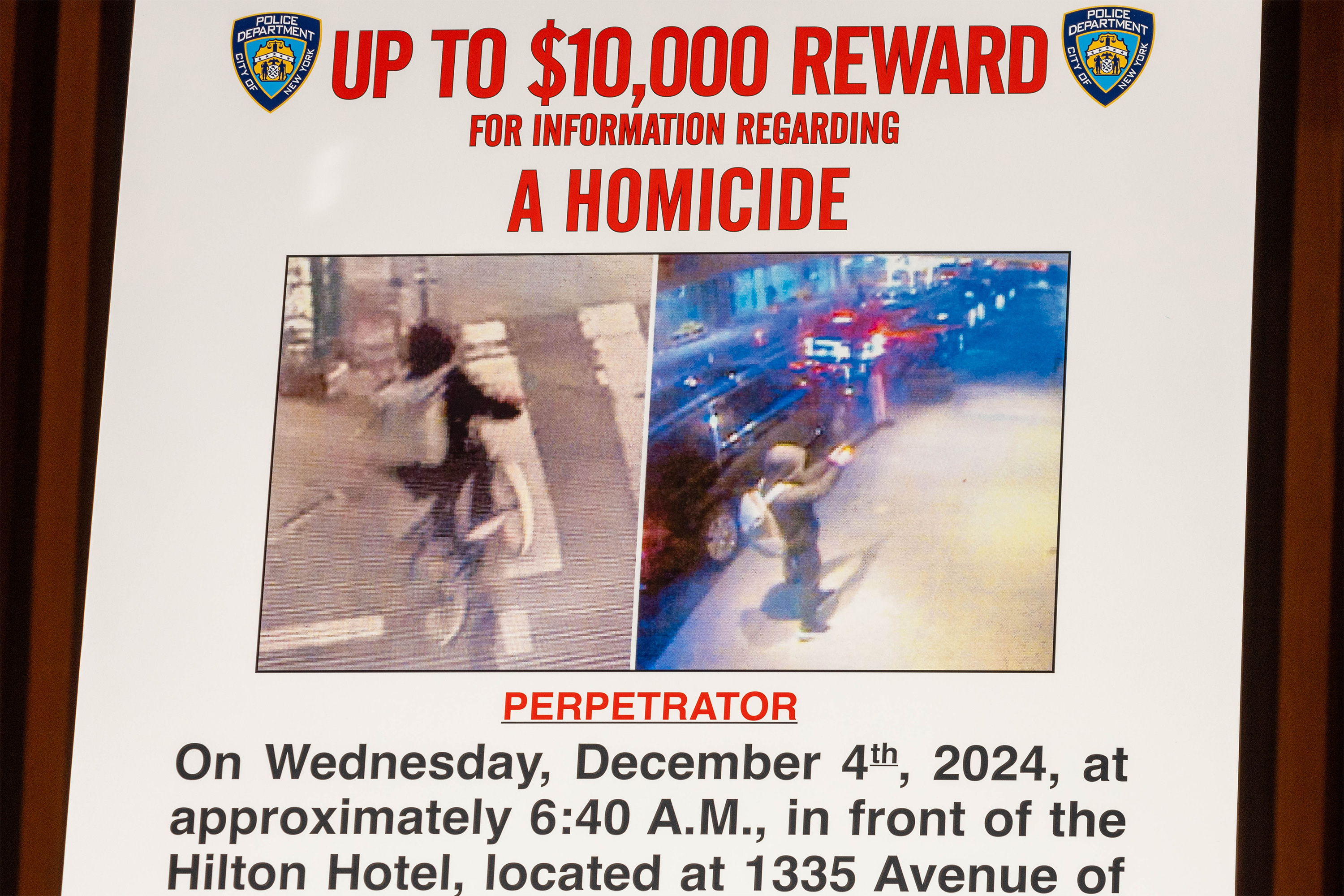 A photo of wanted poster with two images from security footage of a man riding away on a bike and a gunman. Text on the poster reads, "Up to $10,000 reward for information regarding a homicide." 