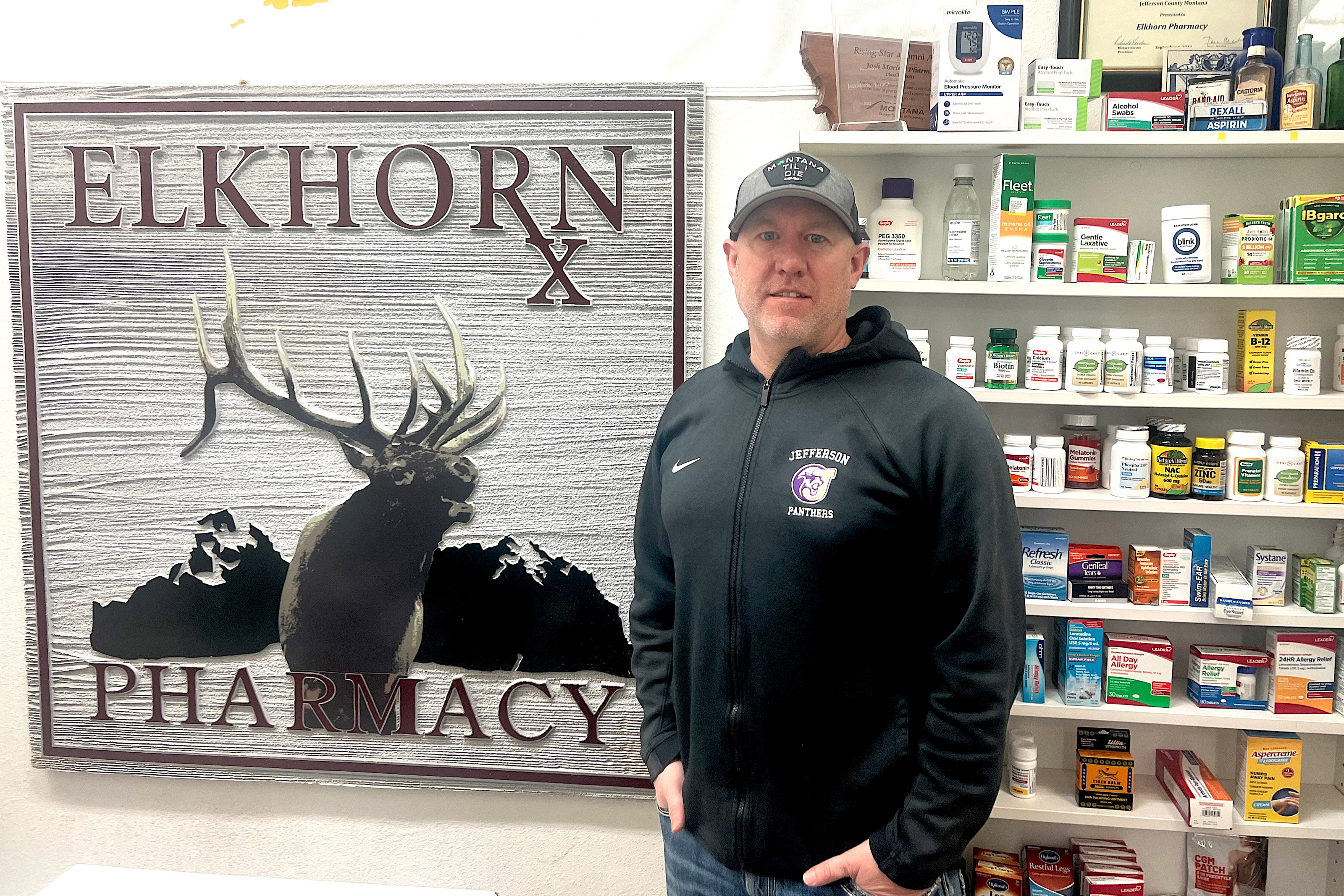 A photo of a man standing for a photo inside a pharmacy named Elkhorn Pharmacy.