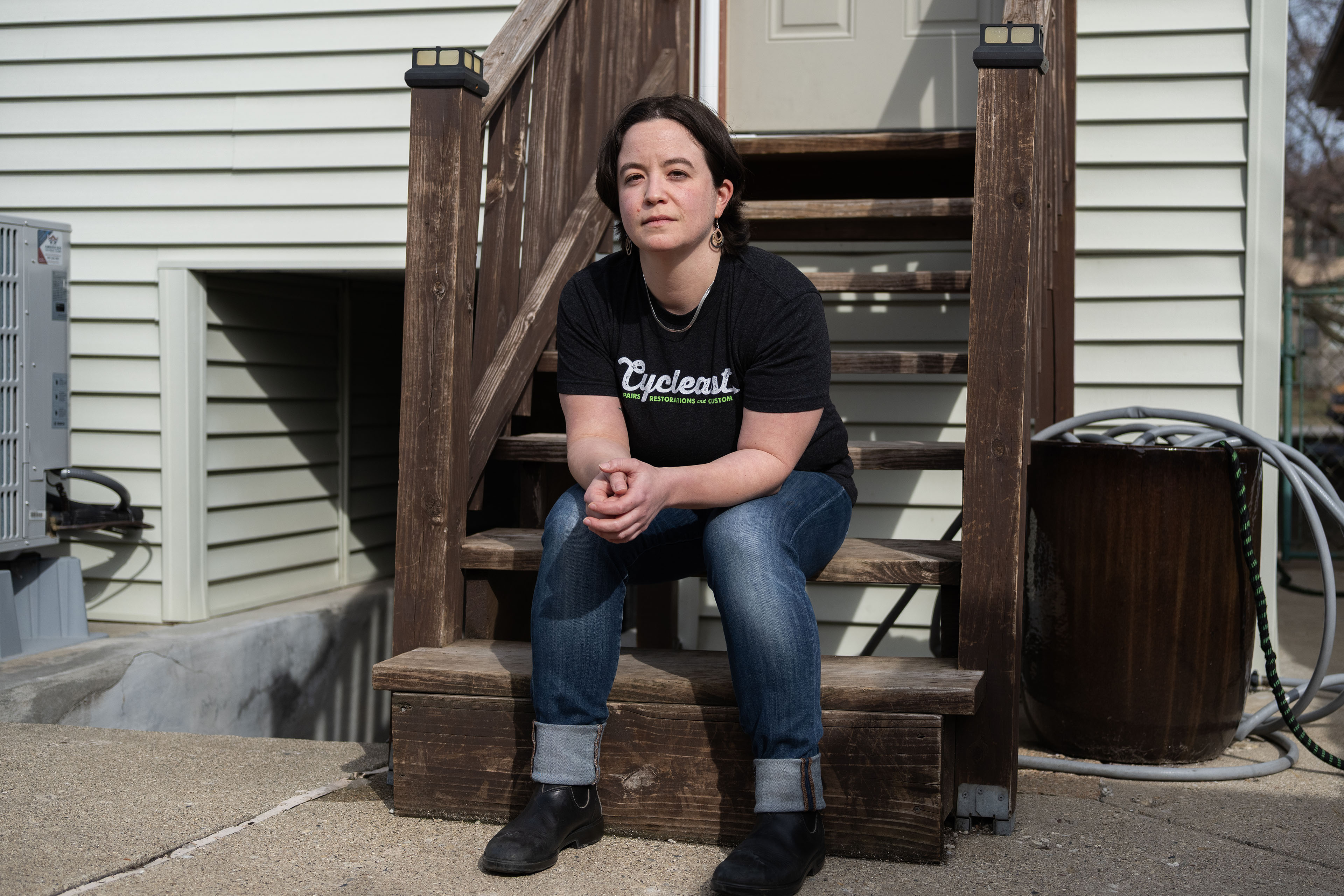 A person wearing a black T-shirt sits on wooden steps.
