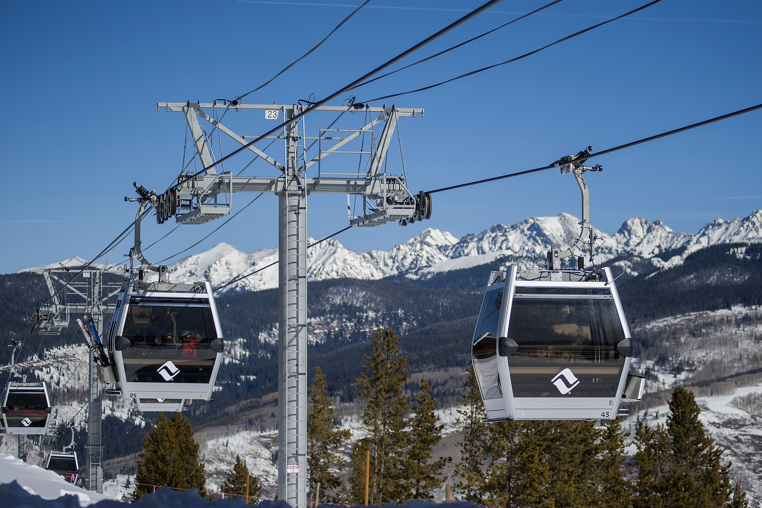 A photo of two gondolas on cables at a ski resort.
