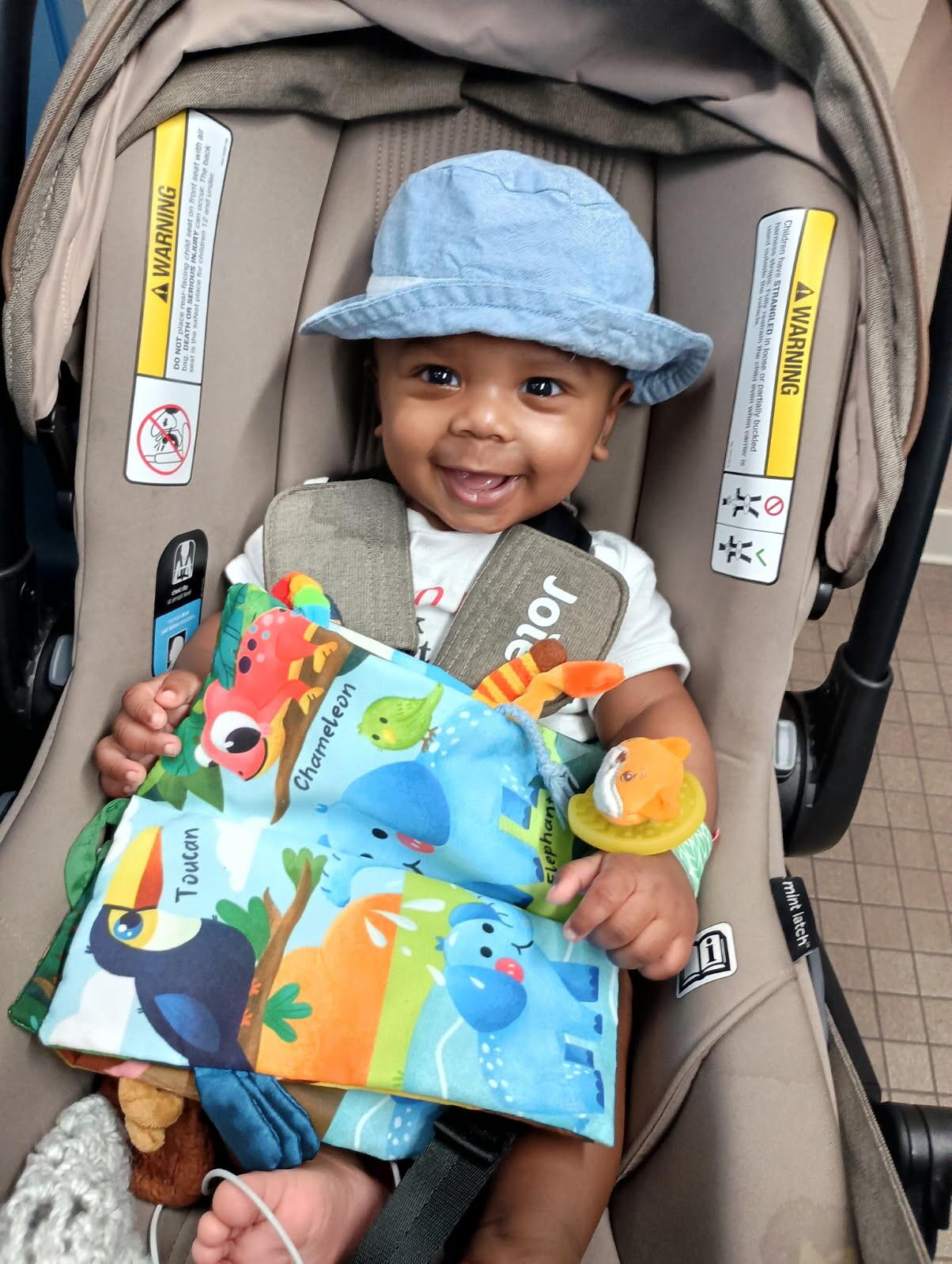 A photo of Ezekiel Tomasek smiling while strapped in a baby carrier.
