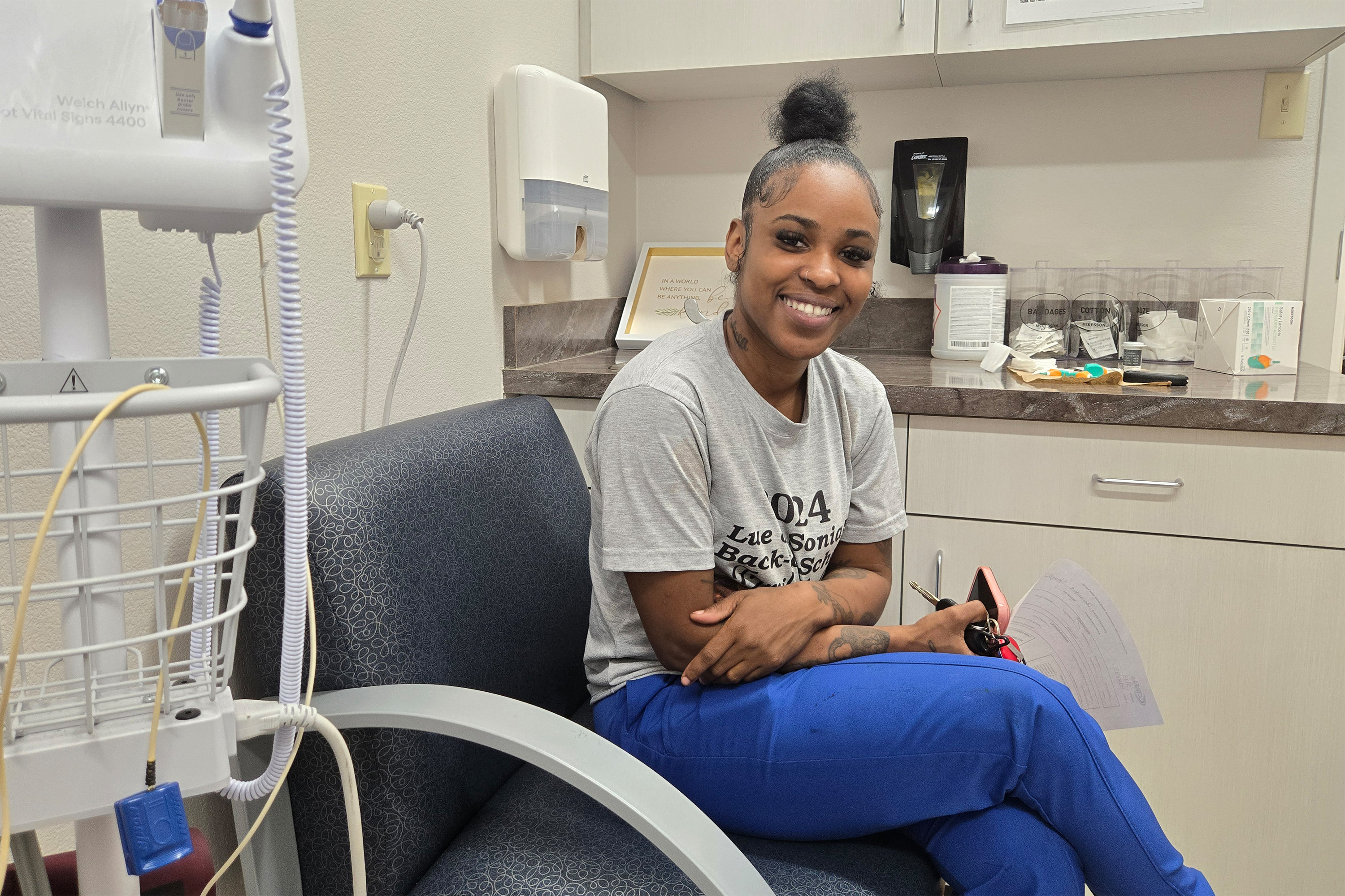 A photo of a woman sitting in a exam room at a community health center.
