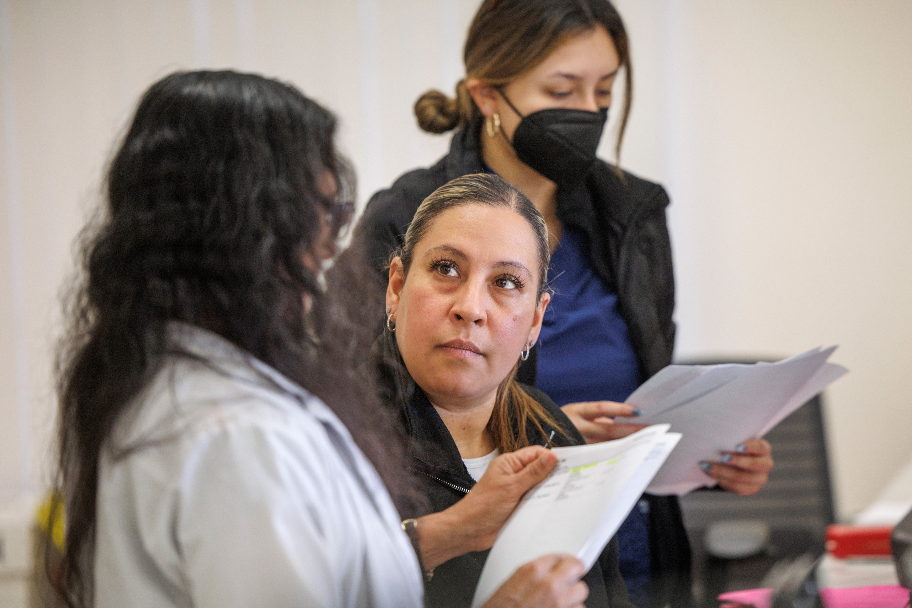 A photo of doctor going over paperwork with two medical assistants in her office.