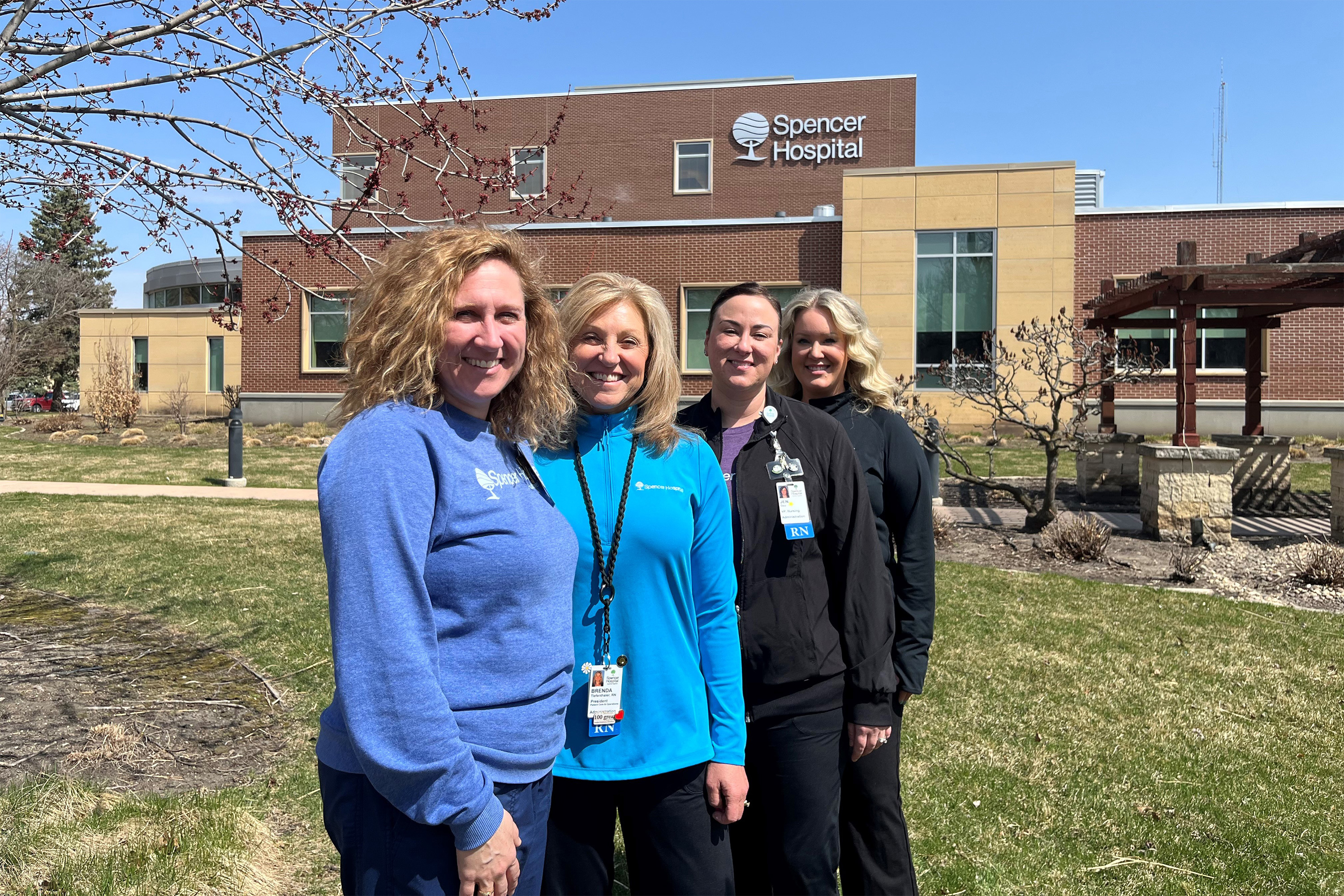 A photo of four women standing together for a photo in front of Spencer Hospital.