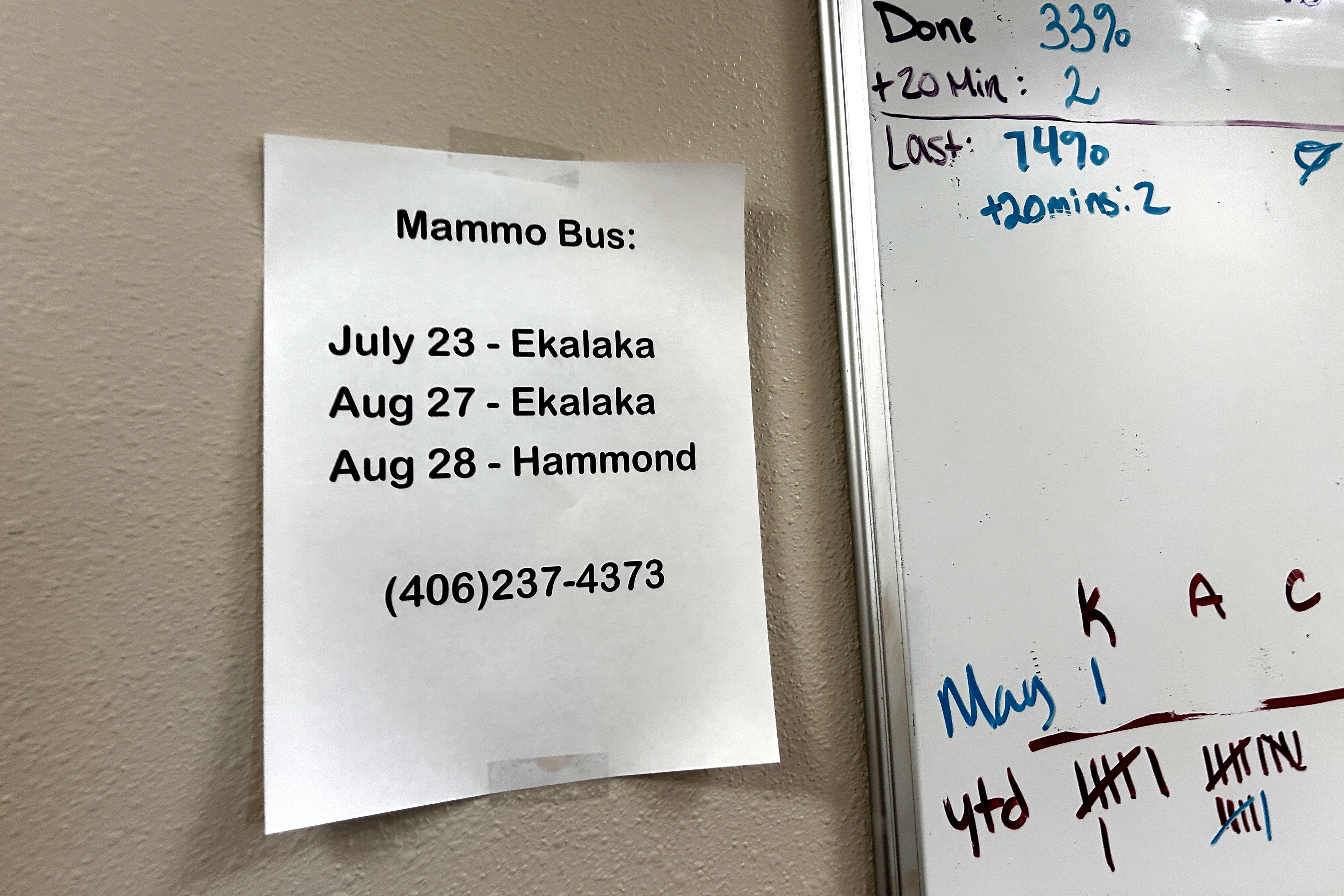 A piece of paper pinned to a wall that reads: "Mammo Bus: July 23 - Ekalaka, Aug 27 - Ekalaka, Aug 28: Hammond' followed by a cell number