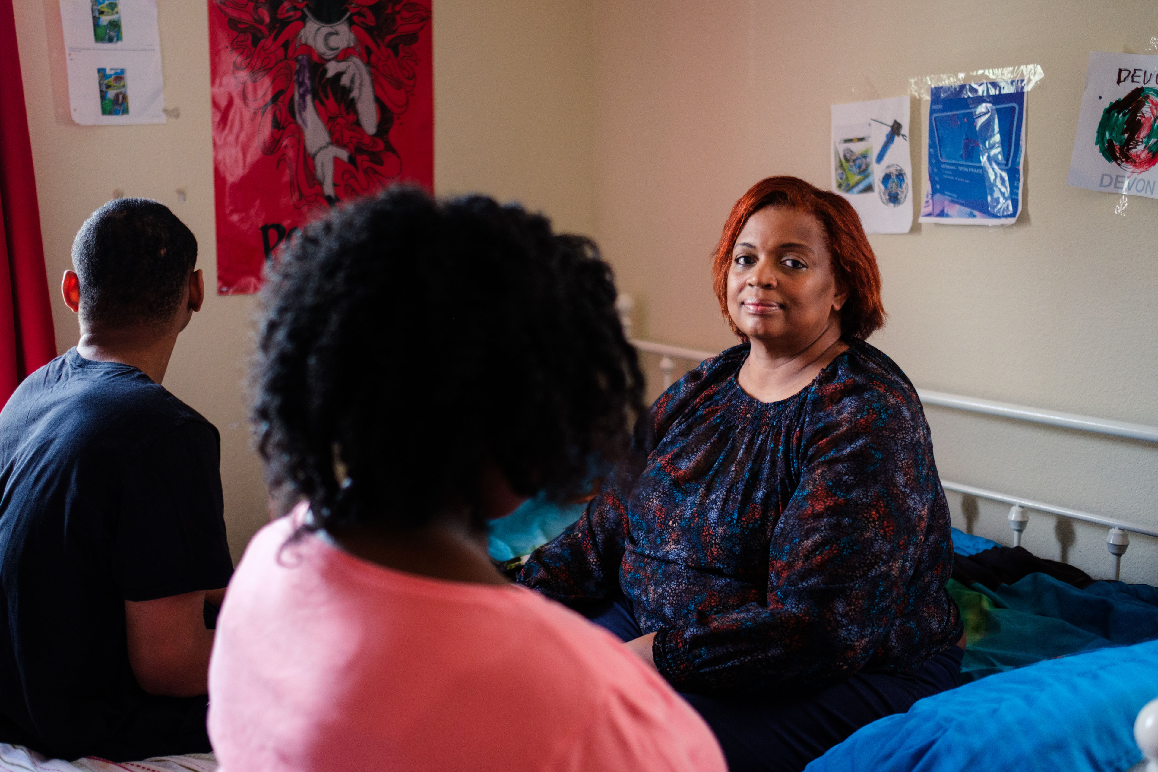 A woman sits facing the camera. Her two children sit near her, with their heads turned away from view.