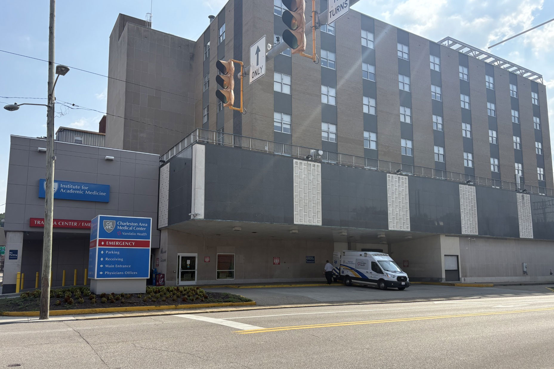 A hospital building is shown at a road intersection with a traffic light.