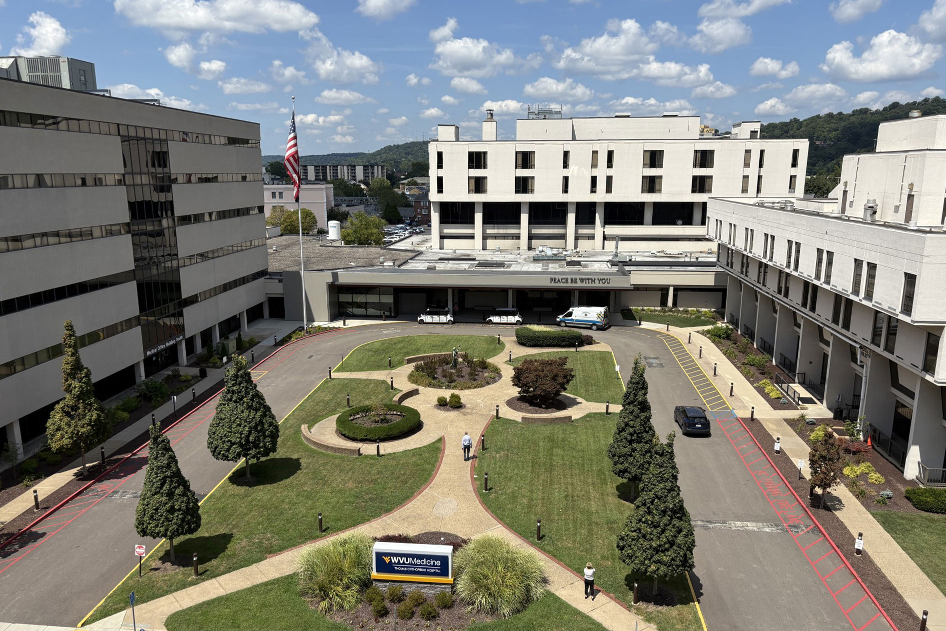 Building surround a road looping around a greenspace with walkways and a sign reading "WVU Medicine".