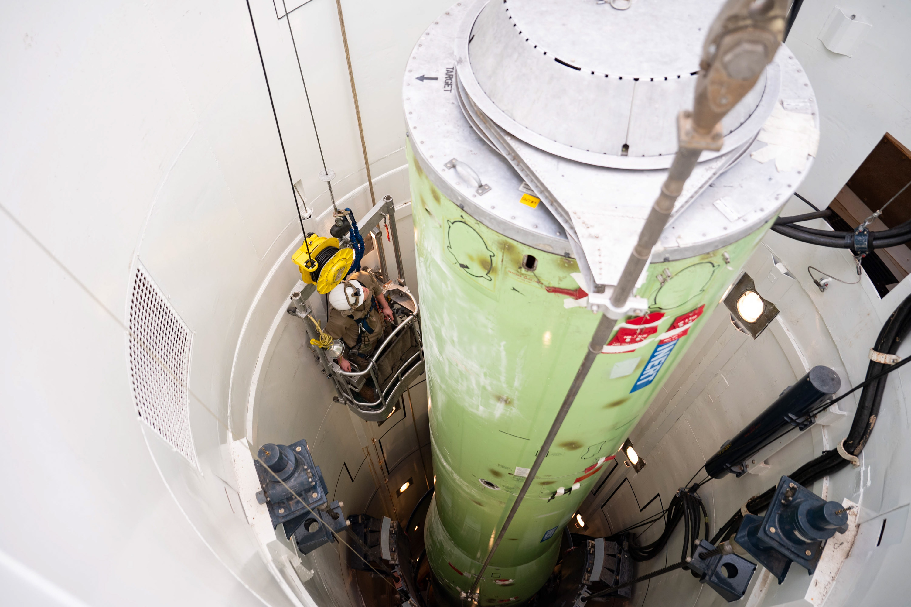 A photo of an airman on a lift inside of a narrow missile silo.