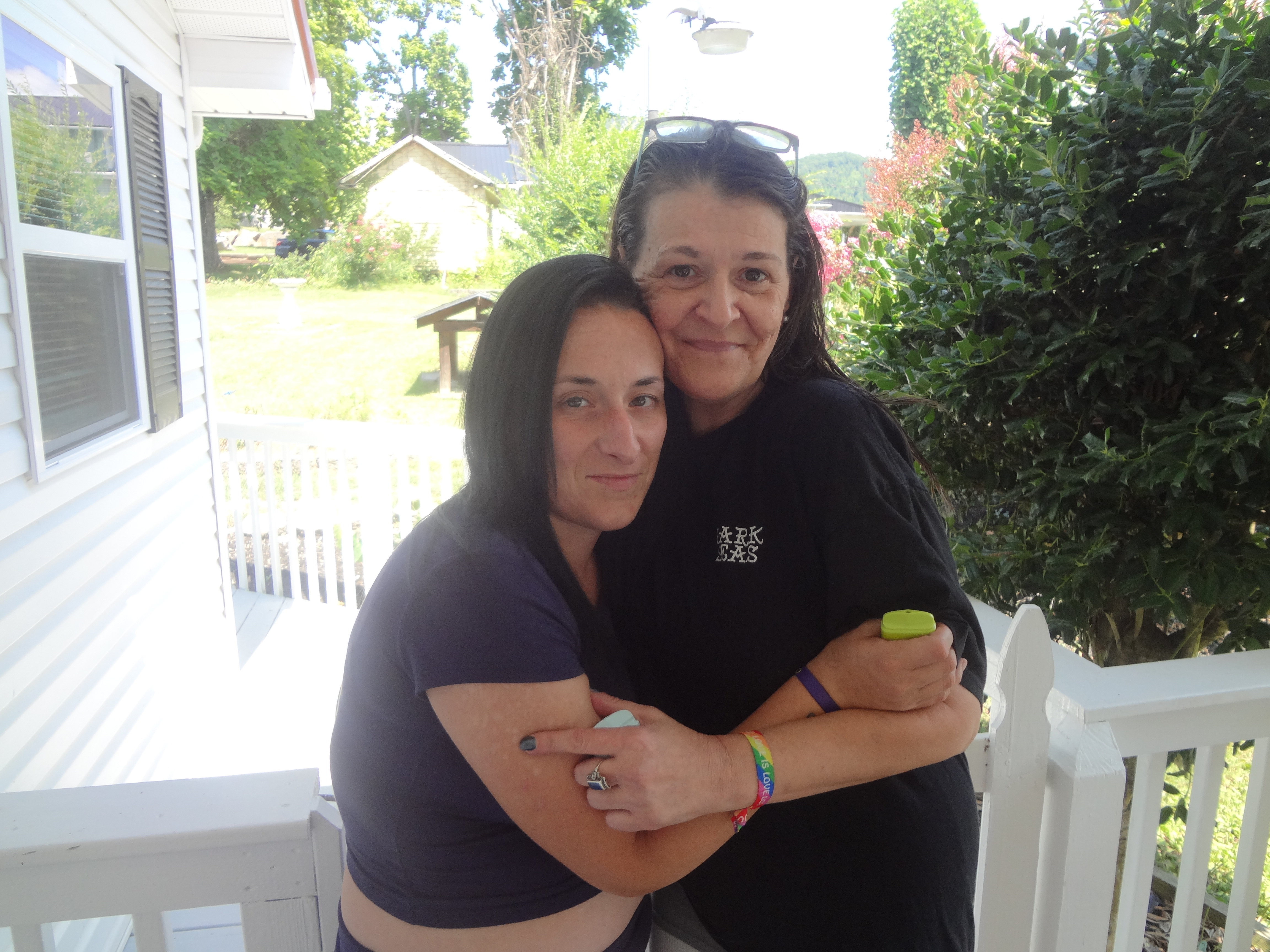 A pair of woman in black tshirts embrace