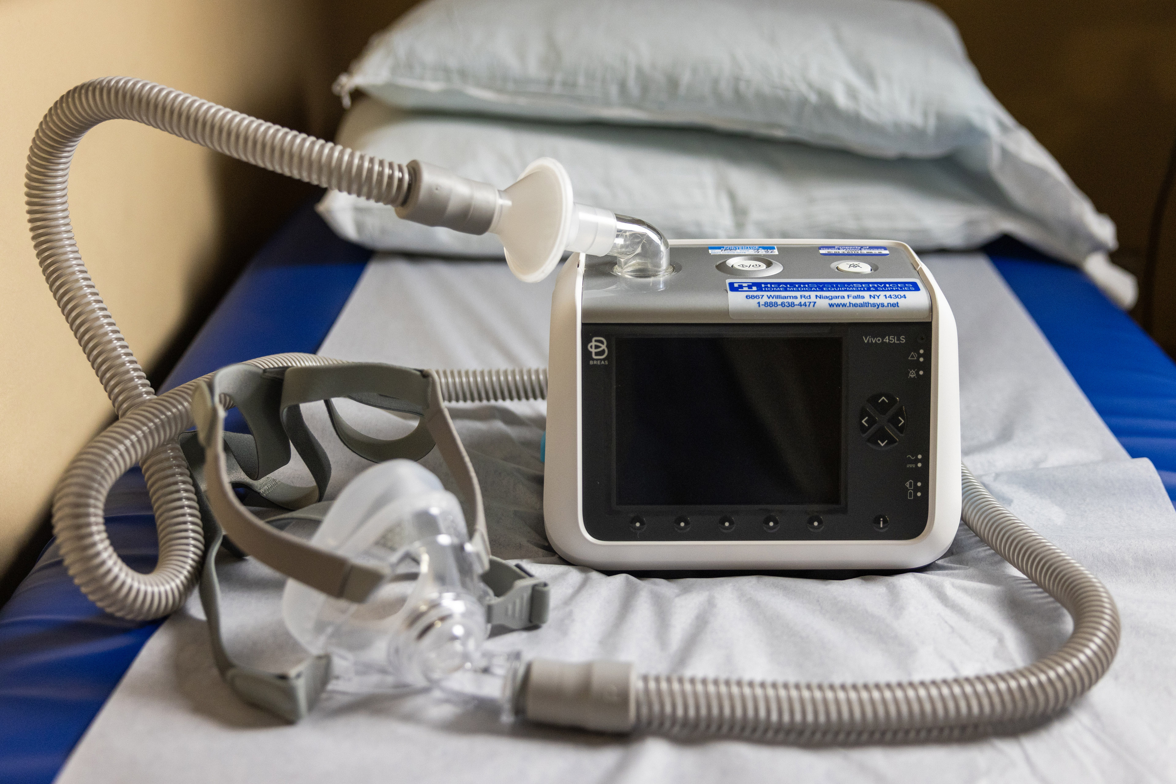 A ventilator sits on a gurney in a hospital exam room