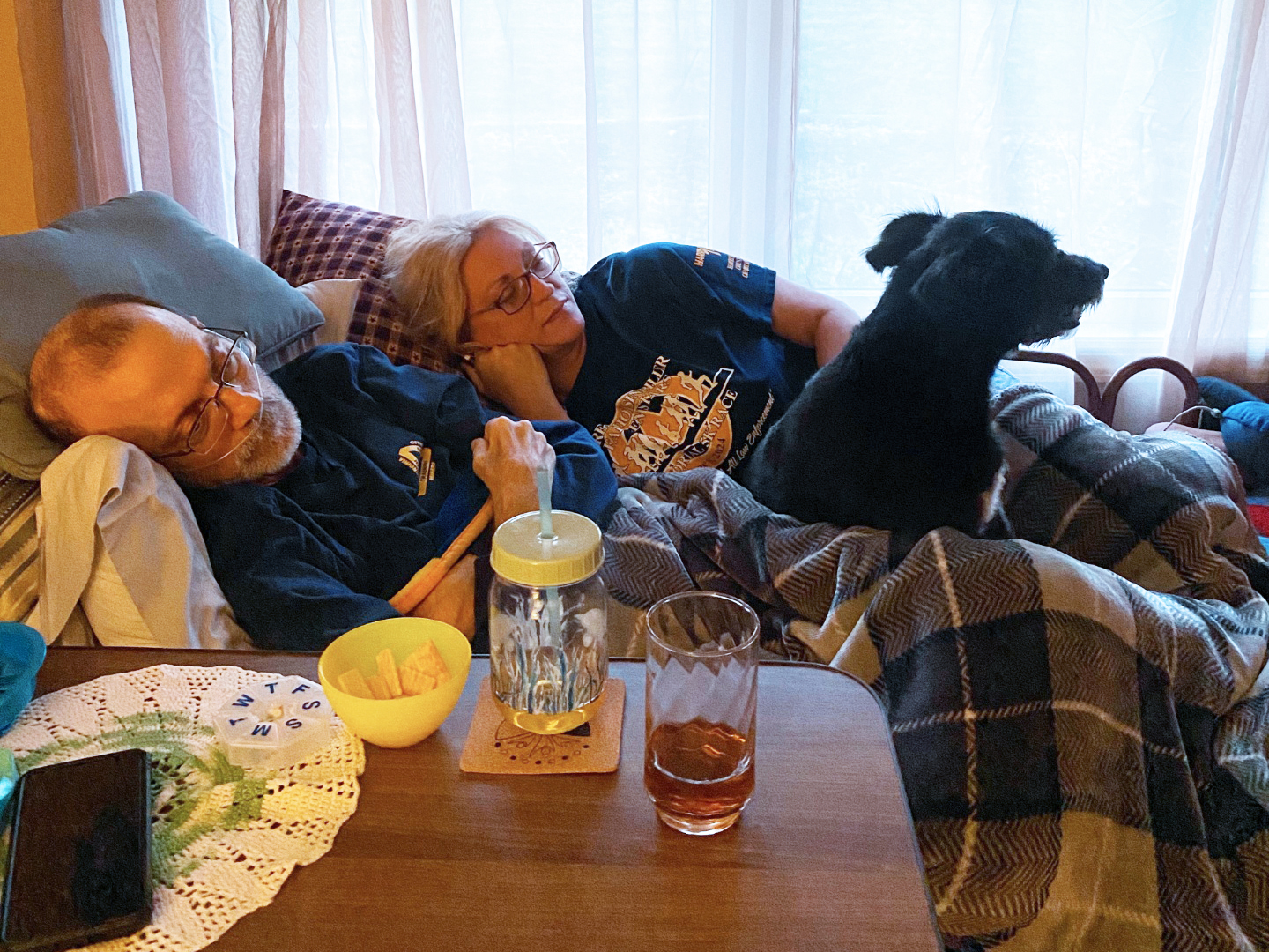 A photo of Eric and Becky Tennant lying down. A dog is with them.