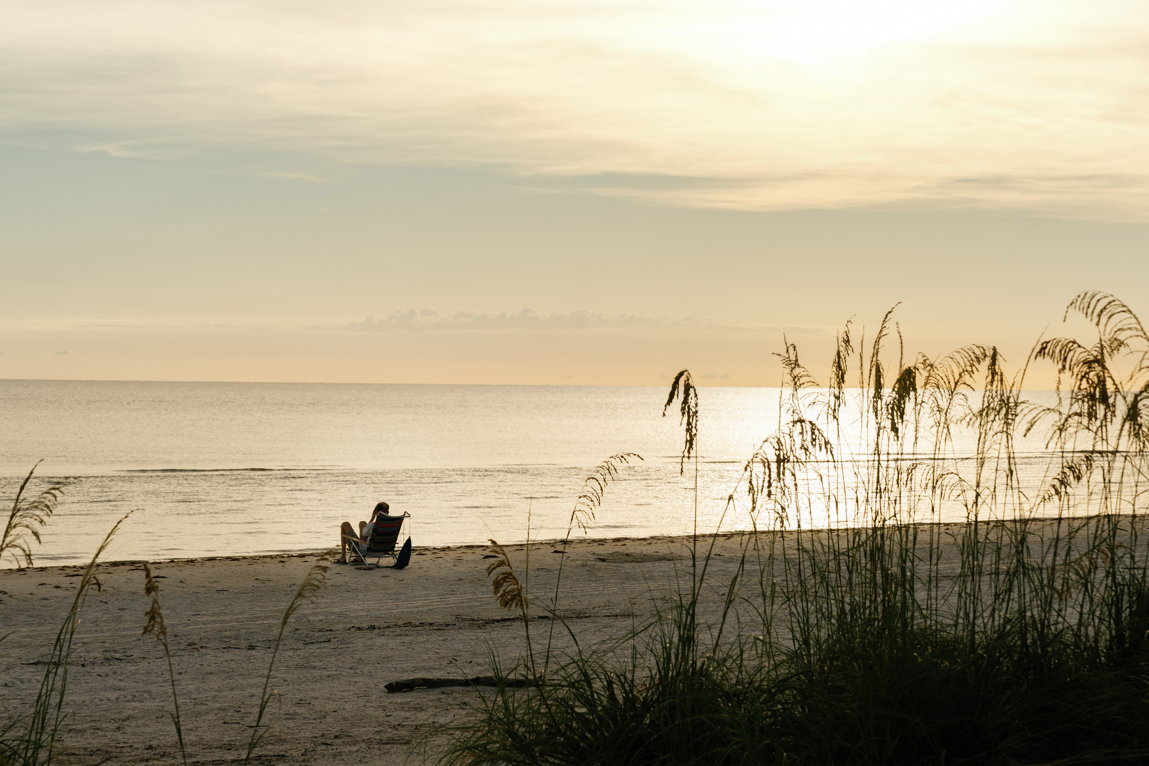 A photo of Eric Tennant from afar. He is lounging in a chair on the beach.