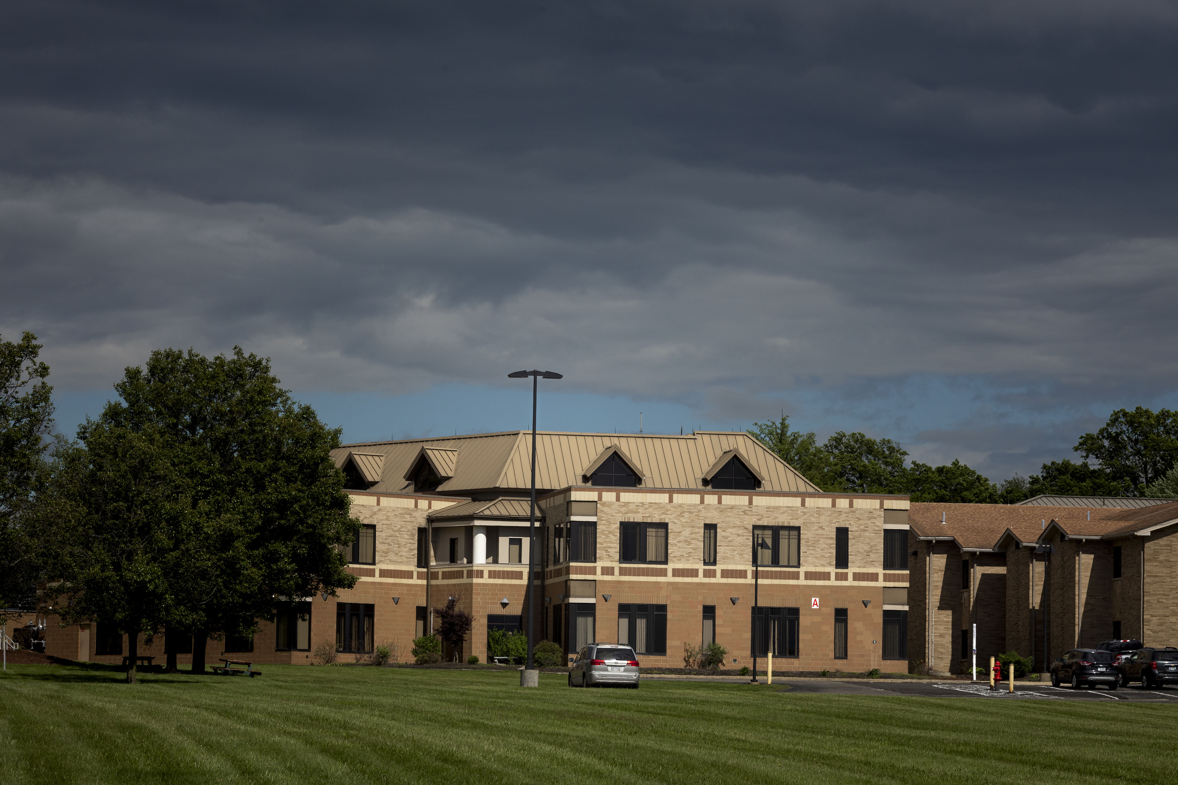 An exterior photograph of a medical building. The sky is half stormy and dark, half clear and blue.