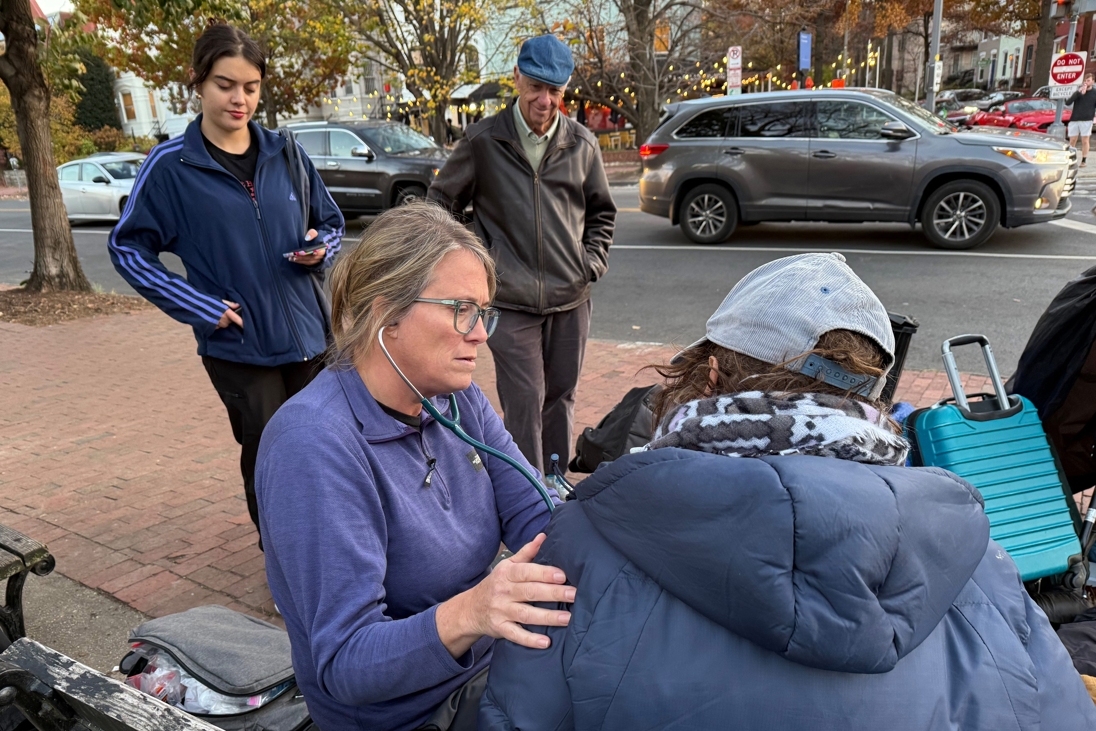A photo of a doctor checking a homeless patient at a park in D.C.
