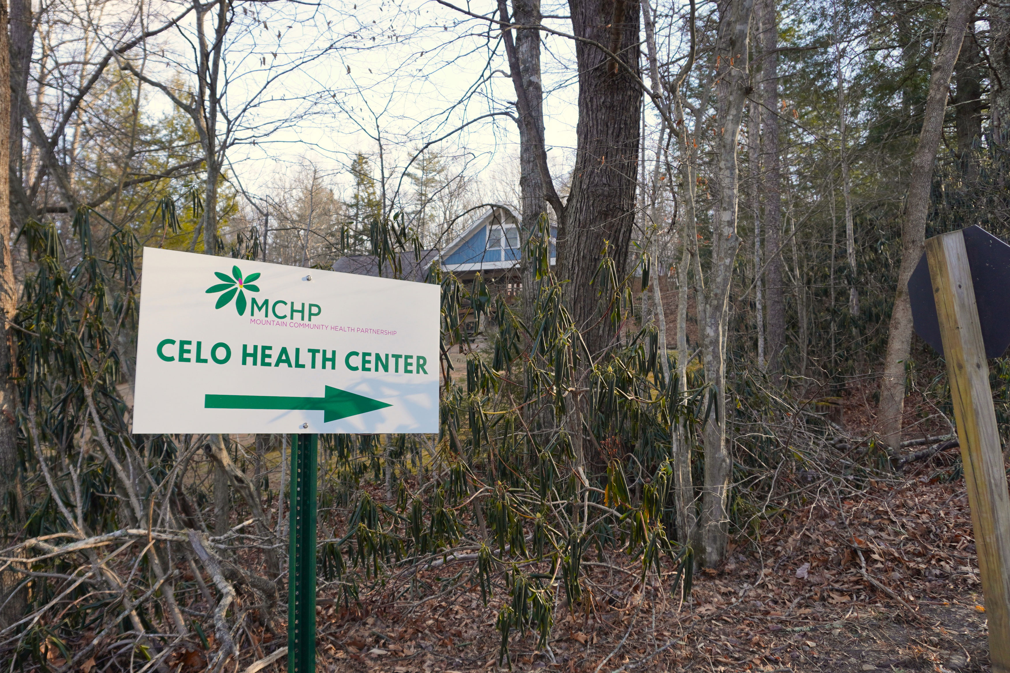 A sign in a wooded area. It reads, "MCHP: Mountain Community Health Partnership. Celo Health Center."