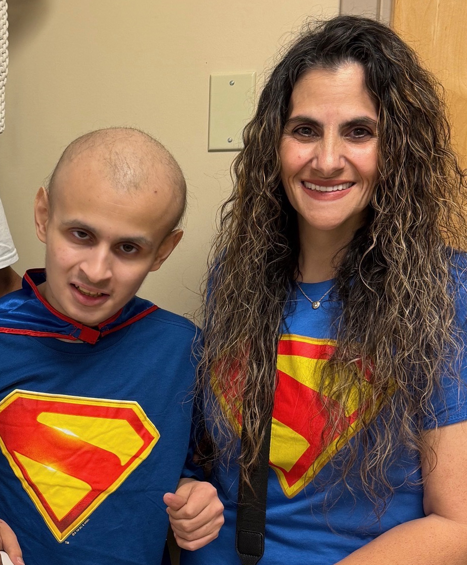Michelle Mastrototaro sits with her son, Bryce. They are both wearing t-shirts with the Superman logo on them.
