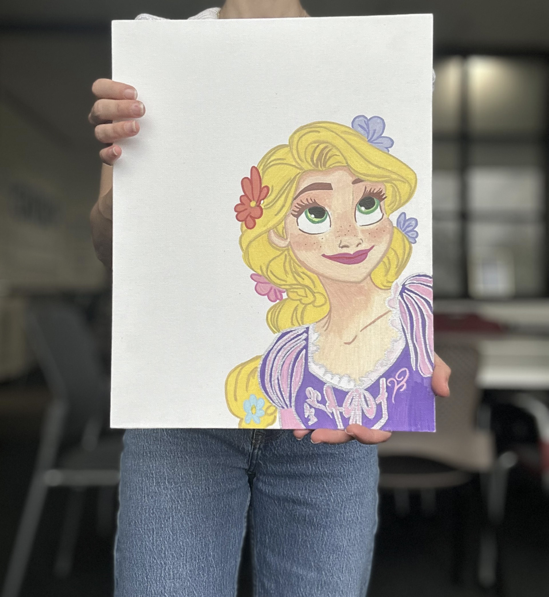 An adult woman holds up a drawing of Disney's Rapunzel.